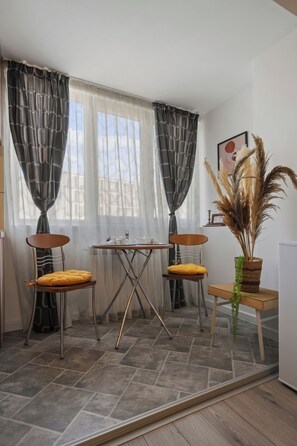 A room with a dining table, two chairs, a potted plant, and a window with curtains. - North Station Studio w. AC (Bucharest)