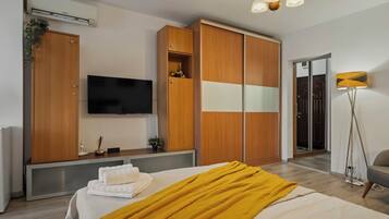 Una habitación de hotel moderna con cama, televisión, armario y lámpara de pie.