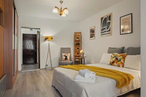 A hotel room with a bed, bedside table, lamp, and artwork on the walls. - North Station Studio w. AC (Bucharest)