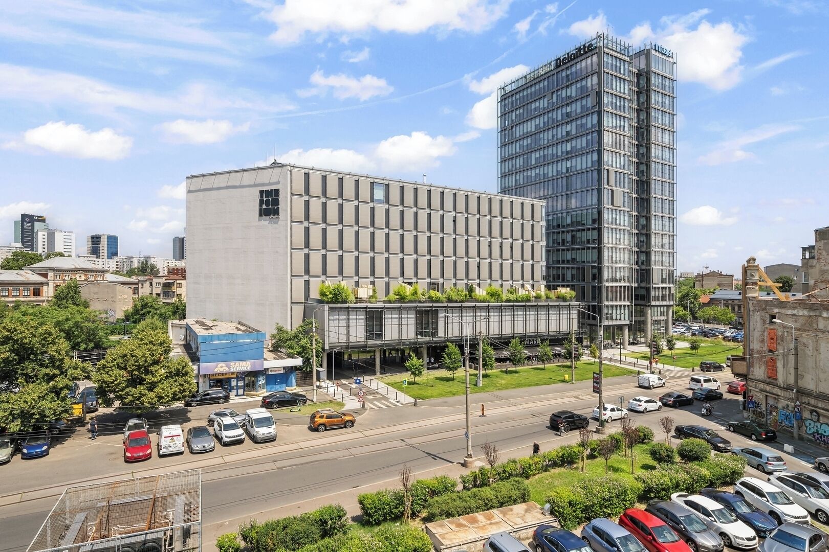 Ein modernes Gebäude mit Glasfassade, einem Parkplatz und einer Straße mit Autos.