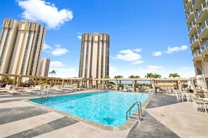 Un espace piscine aménagé sur le toit, avec des chaises longues et une piscine.