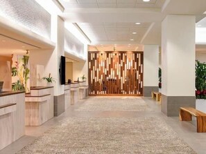 Un espace d’accueil moderne avec un séparateur en bois, un comptoir d’accueil et un sol recouvert de moquette.