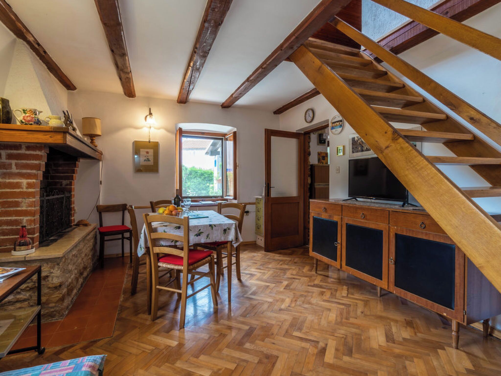 Ein Essbereich mit Tisch und Stühlen, einem Kamin und einer Holztreppe.