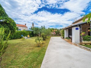 Une cour avec un chemin pavé, une petite pelouse et un bâtiment doté d’un toit en tuiles.
