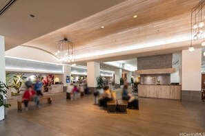 A spacious lobby with a wooden ceiling, a reception desk, and seating areas. - Stunning Ala Moana 1BR W| Balcony & Mountain/City Views (Honolulu)