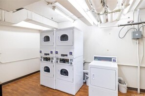 Une buanderie équipée de machines à laver et de sèche-linge superposés, d’une bouche d’aération et d’un panneau de commande.