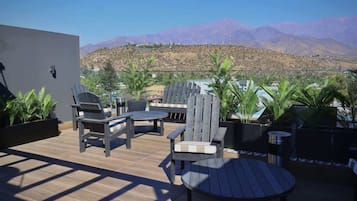 Un patio al aire libre con mobiliario de madera, una mesa redonda y plantas en macetas.