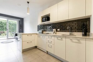 Eine moderne Küche mit Mikrowelle, Kaffeemaschine und einem Messerblock auf der Arbeitsfläche.