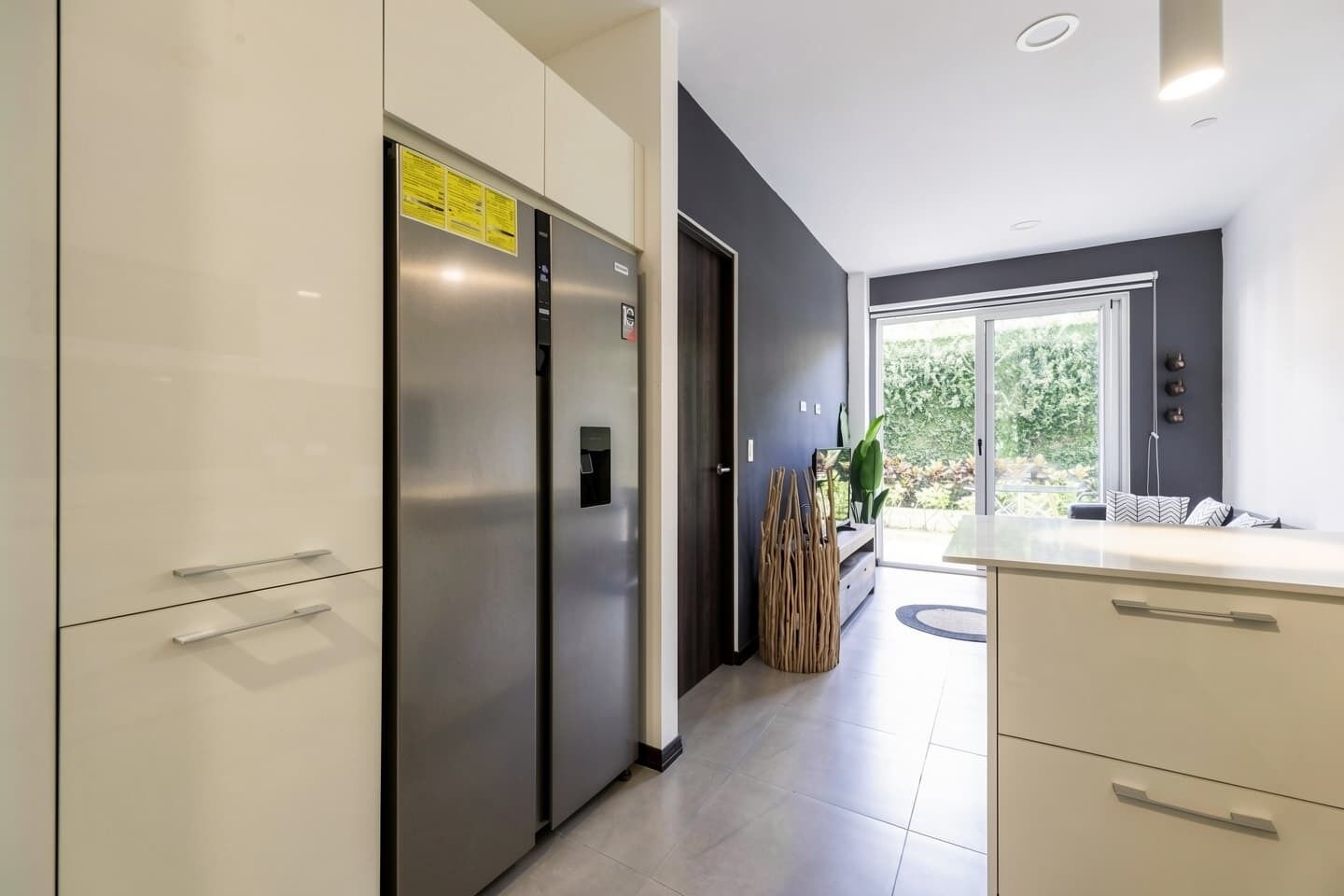 Une cuisine moderne dotée d’appareils électroménagers en acier inoxydable, d’un mur de couleur sombre et d’une fenêtre donnant sur un paysage verdoyant.