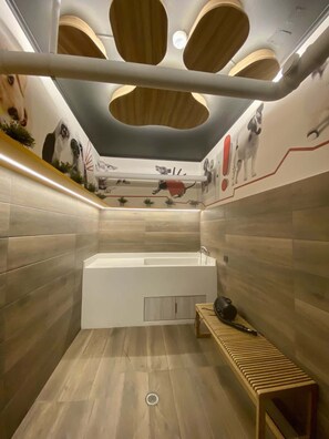 Ein modernes Badezimmer mit einer großen Badewanne, einer Holzbank und einer Decke mit runden Leuchten.