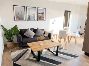 Ein modernes Wohnzimmer mit Sofa, Couchtisch und Essbereich.