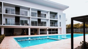 A modern building with a swimming pool, multiple balconies, and outdoor seating. - Corporate Studio in San Jose Urban Flats Building (Pozos)