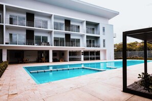 A modern building with a swimming pool, multiple balconies, and outdoor seating. - Corporate Studio in San Jose Urban Flats Building (Pozos)