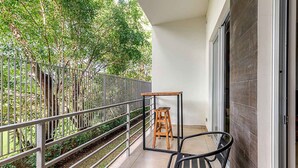 A balcony with a metal railing, a wooden stool, and a chair. - Corporate Studio in San Jose Urban Flats Building (Pozos)