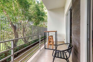 A balcony with a metal railing, a wooden stool, and a chair. - Corporate Studio in San Jose Urban Flats Building (Pozos)