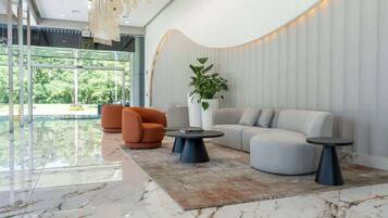 Un vestíbulo moderno con una pared curva, un sofá, dos sillones, una mesa de centro y una planta en maceta.
