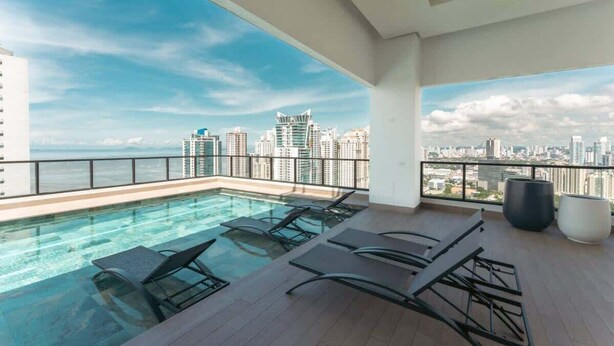 A rooftop pool with lounge chairs, a city skyline view, and a modern building in the background. - Serviced Studio with City & Ocean View in Panama U902 (Panamá)
