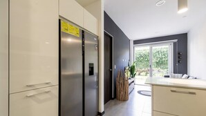 Uma cozinha moderna com eletrodomésticos de aço inoxidável, uma parede escura e uma janela com vista para o verde.