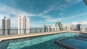 Una piscina en la azotea con vista al horizonte urbano, rodeada de edificios altos.