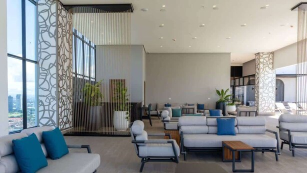 A spacious lounge area with sofas, armchairs, and a coffee table, featuring large windows and a city view. - Service Studio with Ocean Views in Panama City (Panamá)