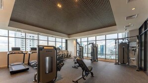 Een sportschool met loopbanden, krachtapparaten en een groot raam met uitzicht op de stad.