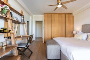 A bedroom with a wooden bed, a desk with a chair, a ceiling fan, and a wardrobe. - Perfect Views, Sleeps 6, Mouille Point - Emerald Horizon (Cape Town)