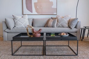 A living room with a grey sofa, patterned cushions, a black coffee table, and a decorative vase. - Family Villa, Pool, Ocean Views - Camps Bay Grace (Cape Town)