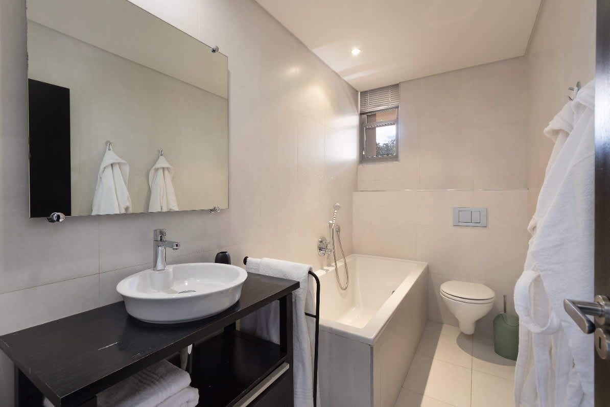 A modern bathroom with a white sink, a bathtub, and a toilet.