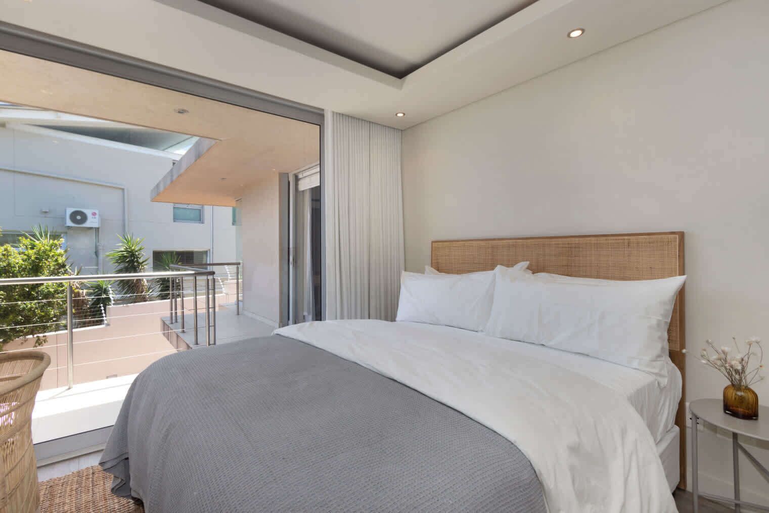Une chambre d’hôtel moderne dotée d’un grand lit, d’un balcon avec vue et d’une porte-fenêtre coulissante donnant sur l’extérieur.