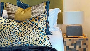 A bed with patterned pillows, a black throw blanket, a wooden nightstand with a lamp, and a geometric rug. - Location, Luxury, Sea Point, Views -Topaz Views Apt (Cape Town)