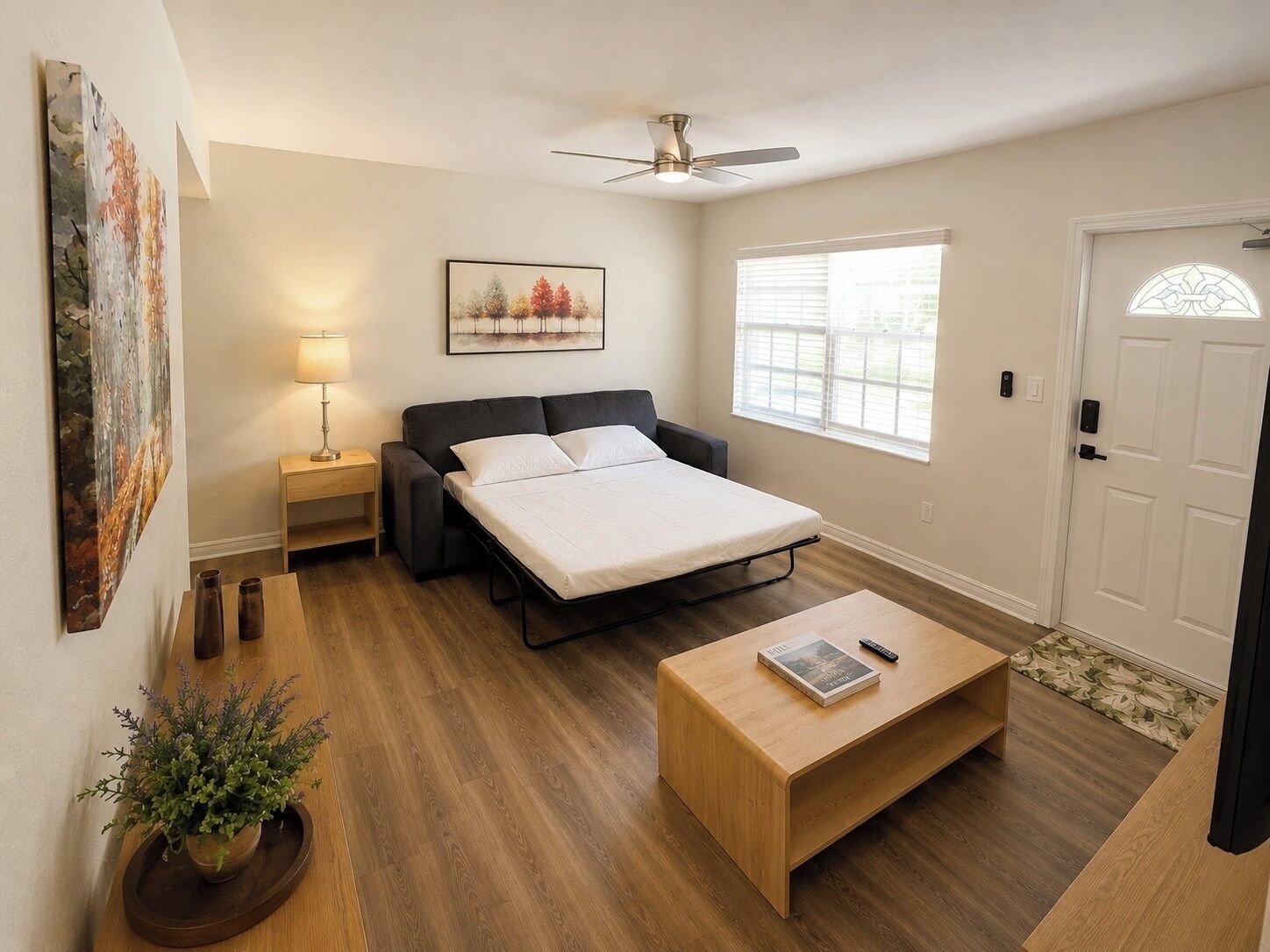 Un dormitorio con cama, mesita de noche, lámpara y ventana.