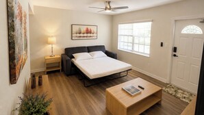 Quarto com cama, mesa de cabeceira, luminária e janela.