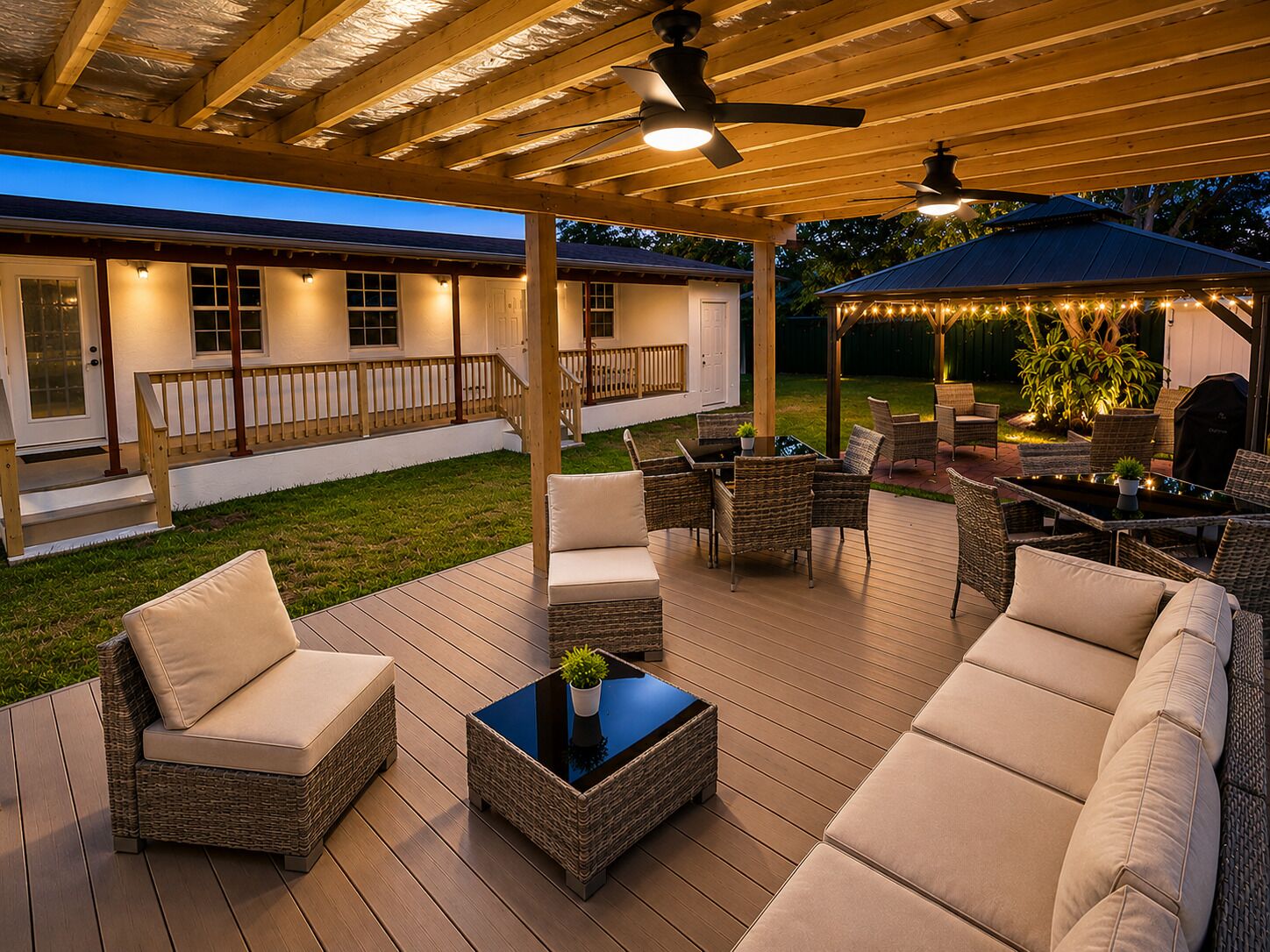 A covered outdoor patio with wicker furniture, a table, and a ceiling fan.