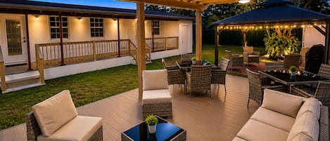 A covered outdoor patio with wicker furniture, a table, and a ceiling fan.