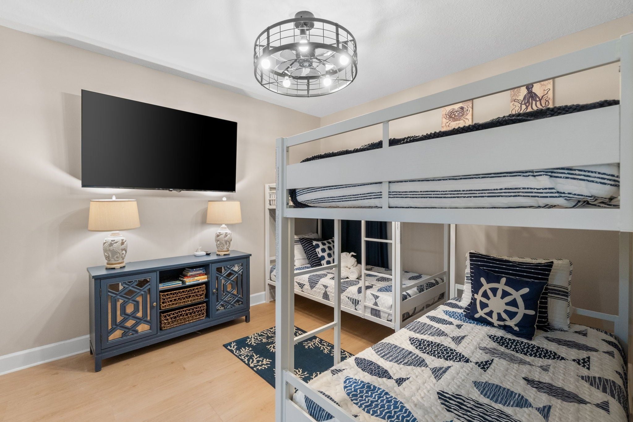 A room with bunk beds, a TV, a console table, and a decorative ceiling light.