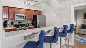 Eine moderne Küche mit Holzausbau, Edelstahlgeräten und einer Bar mit blauen Stühlen.