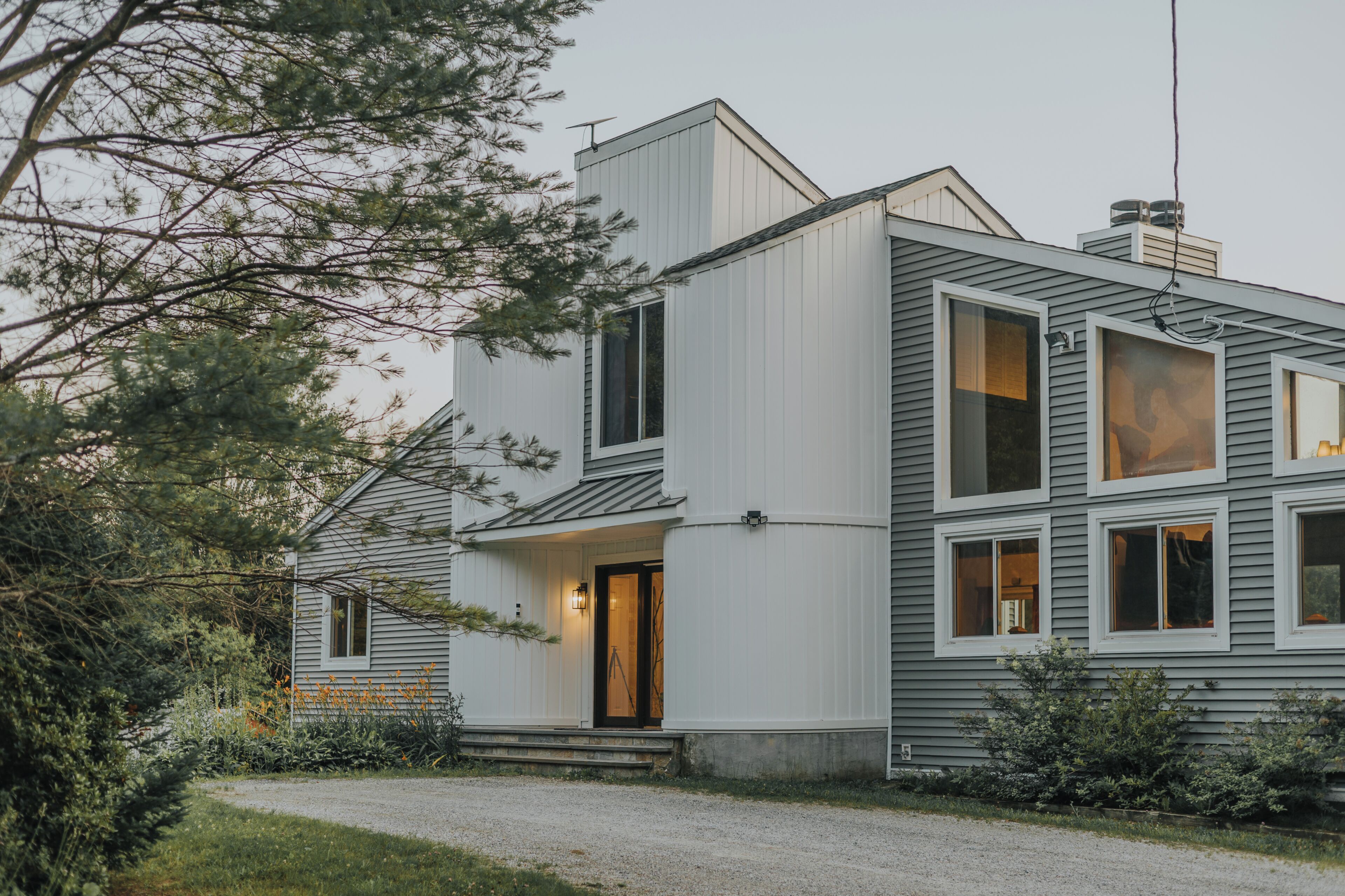 A modern two-story house with a sloped roof, large windows, and a visible chimney.
