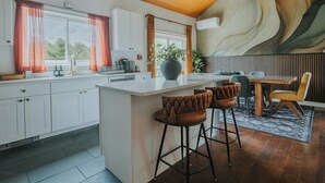 Una cocina moderna con una isla central, taburetes de bar y un comedor con una mesa y sillas de madera.