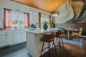 Eine moderne Küche mit einer zentralen Kochinsel, Barhocker und einem Essbereich mit Holztisch und Stühlen.
