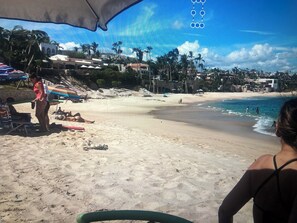 Una platja amb cel blau, palmeres i poques persones.