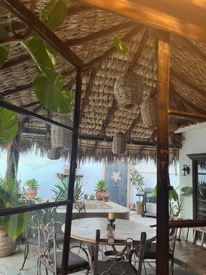 A covered outdoor seating area with a thatched roof, potted plants, and a stone table. - Los Cabos Retreat
3/3 home, 24 Hr. security, private pool gated compound (San José del Cabo)