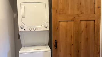 A laundry room with a front-loading washer and dryer, a wooden door, and a metal track system above the door.