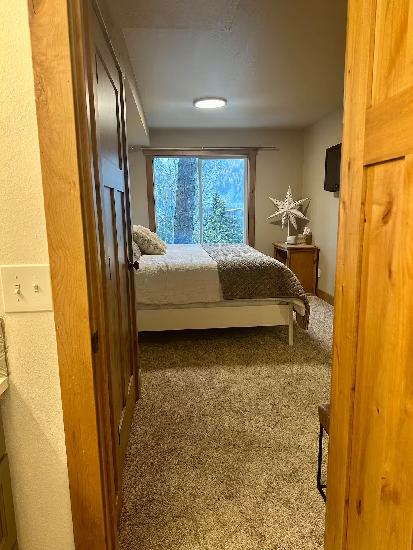 A bedroom with a bed, a window, a star decoration, and a nightstand.