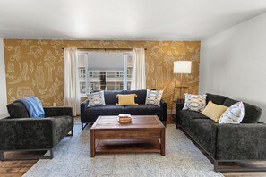 Una sala de estar con un conjunto de sofá, una mesa de centro y papel tapiz estampado.