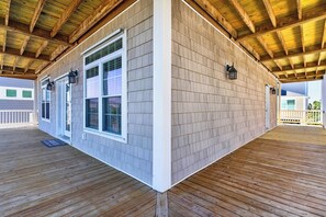 Eine überdachte Terrasse mit Holzbalken, einer weißen Außenwand und einem Fenster mit einer Tür.