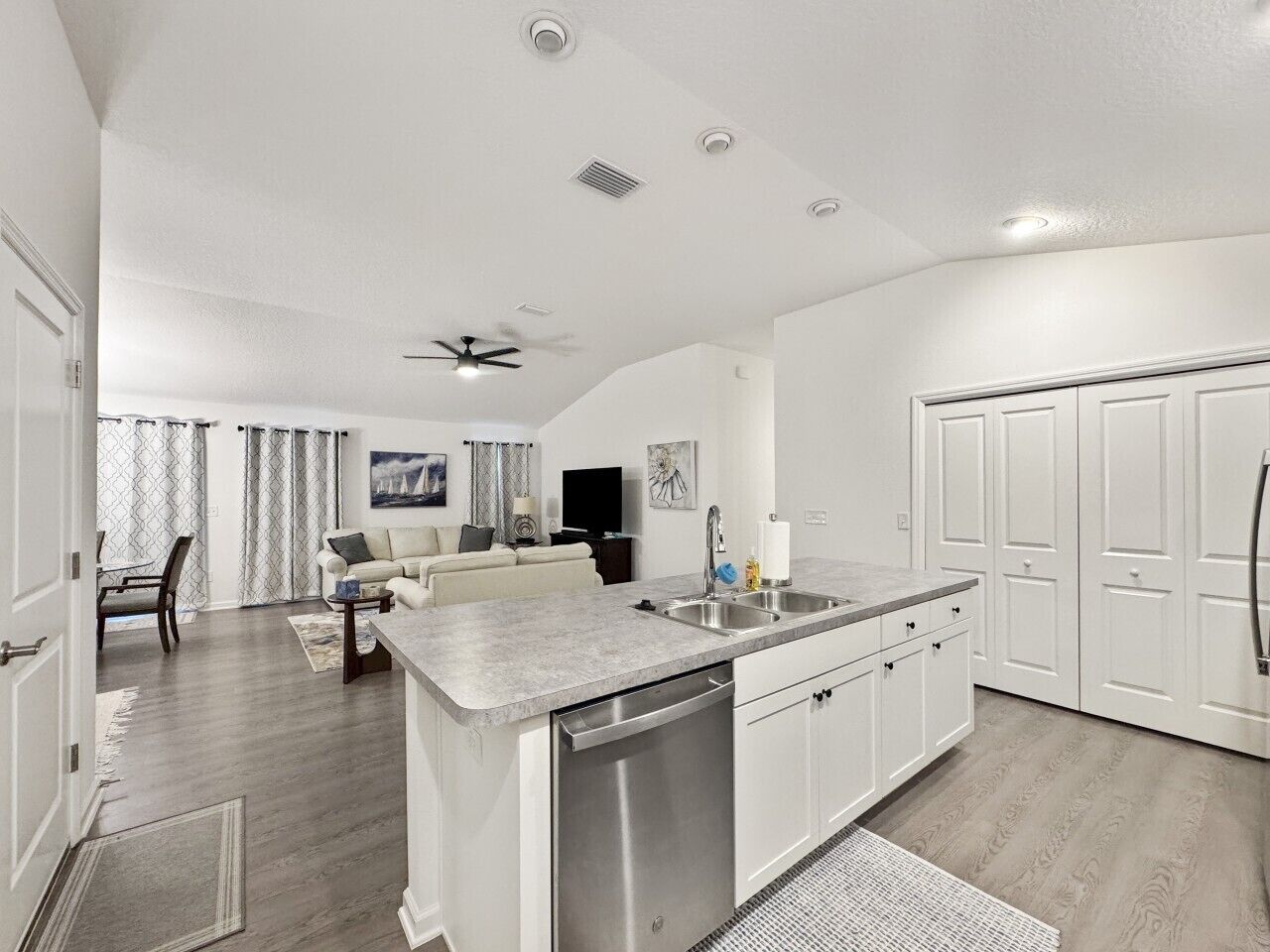 Une cuisine moderne dotée d’un îlot central, d’appareils électroménagers intégrés et d’un coin repas avec un canapé et un téléviseur.