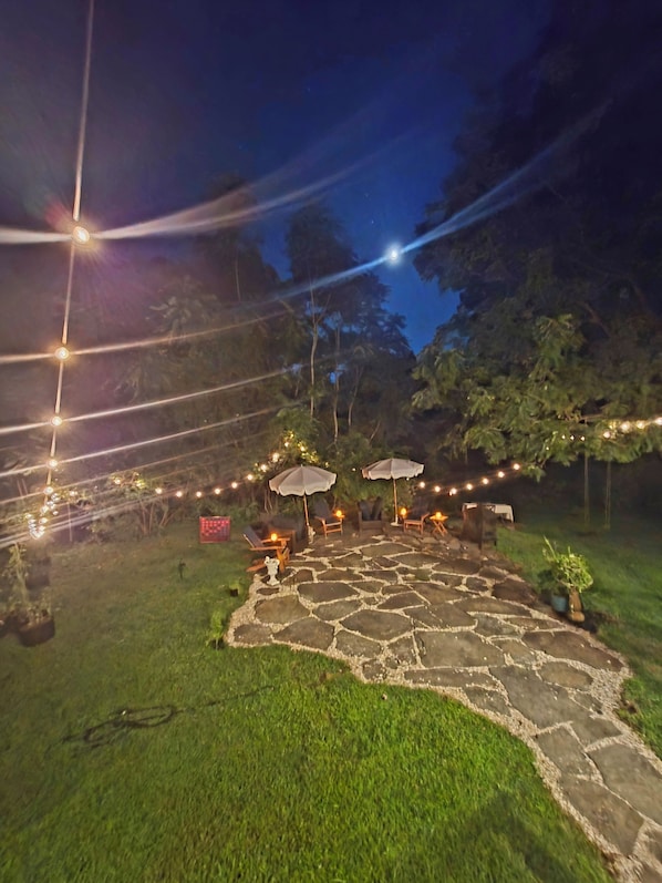 An outdoor patio area with stone flooring, outdoor seating, and string lights. - Historic 1825 Chesapeake Farm Stay  (St. Leonard)