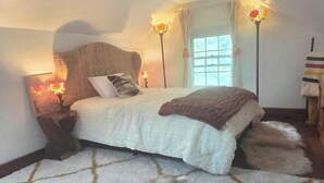 A bedroom with a large bed, two bedside lamps, a window with curtains, and a fluffy rug. - Historic 1825 Chesapeake Farm Stay  (St. Leonard)