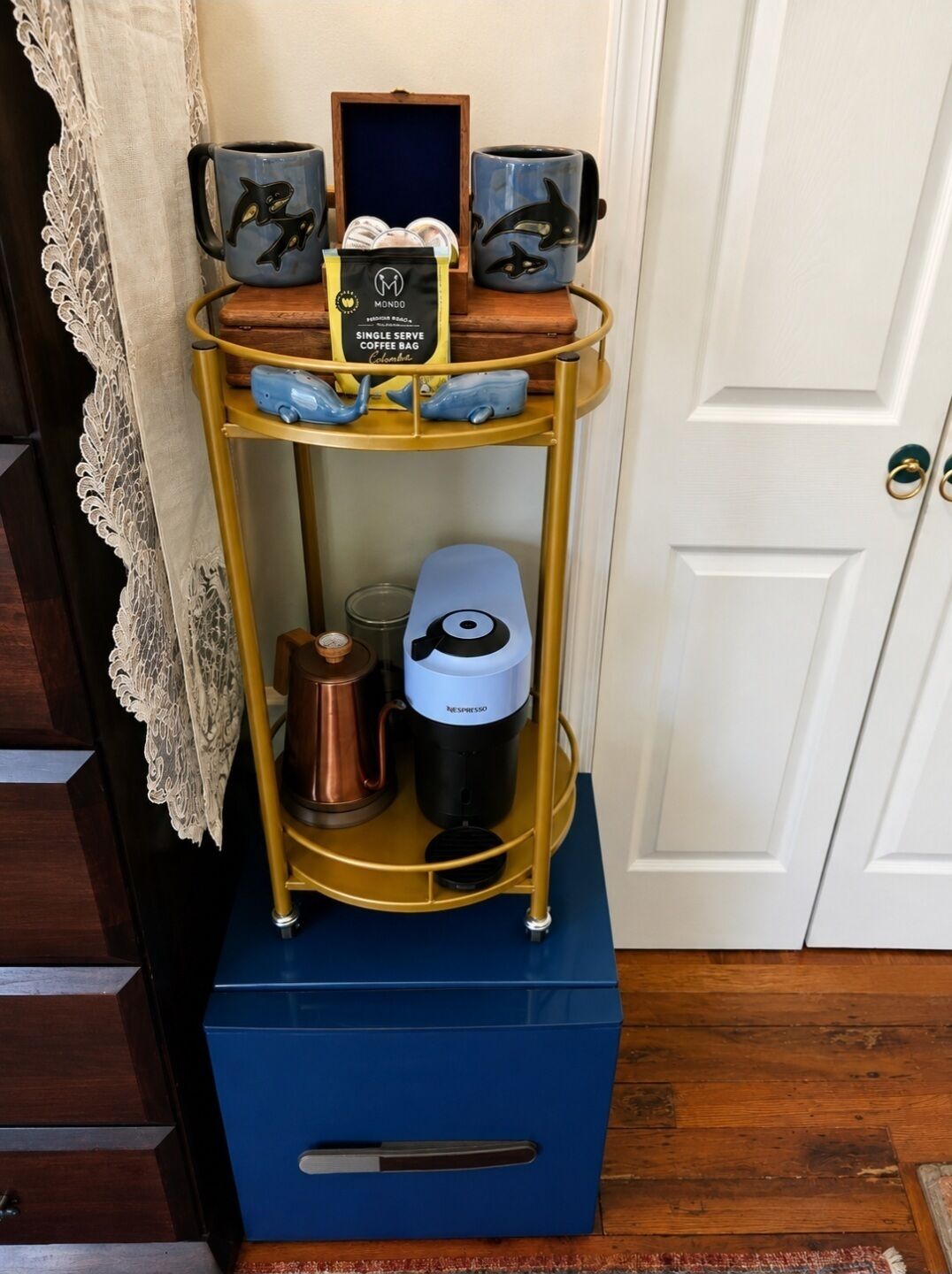 A coffee station with a single serve coffee bag, a coffee maker, and two mugs with dolphin designs.