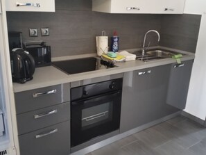Uma cozinha moderna com forno embutido, pia e cafeteira.